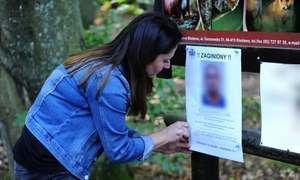 Kobieta rozwieszająca plakat z wizerunkiem zaginionej starszej osoby