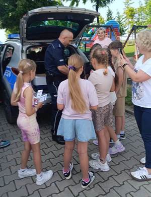 Dzielnicowy na pikniku obok radiowozu wraz z dziećmi