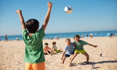 &quot;Grupa dzieci gra w piłkę na plaży.&quot;
