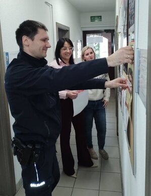 Dzielnicowy zawiesza plakat promujący plebiscyt