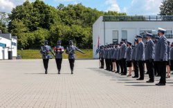 &quot;Trzech policjantów kompanii honorowej ze złożona flagą idzie wzdłuż ustawionych na placu mianowanych&quot;