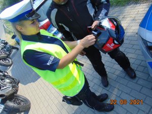 Kontrola drogowa motocyklistów, policjantka wydziału ruchu drogowego naklej na kask pomarańczową kropkę