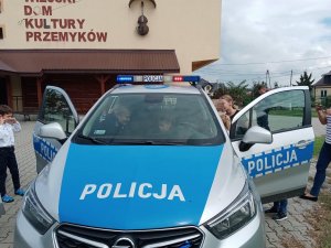 Dzieci podczas oglądania radiowozów. Pomagają policjanci.