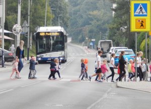 &quot;Dzieci przechodzące przez jezdnię. Na pierwszym planie znak przejścia dla pieszych.&quot;