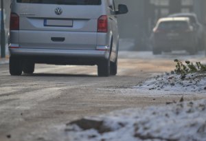 &quot;Zbliżenie na zaśnieżoną i oblodzoną nawierzchnię drogi po której porusza się samochód (widać fragment samochodu – widok z tyłu).&quot;