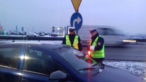 &quot;Policjanci ruchu drogowego stoją obok pojazdu zatrzymanego do kontroli drogowej i rozmawiają z kierowcą&quot;