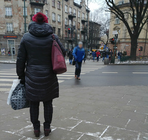 &quot;Tłum pieszych porusza się chodnikiem w rejonie skrzyżowania. Część z nich przechodzi przez jezdnię przy nadawanym na sygnalizatorze świetlnym czerwonym świetle&quot;