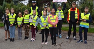 Wspólne zdjęcie dzieci ze Szkoły Podstawowej w Żębocinie wraz z policjantami z KPP Proszowice. Dzieci ubrane w kamizelki odblaskowe.