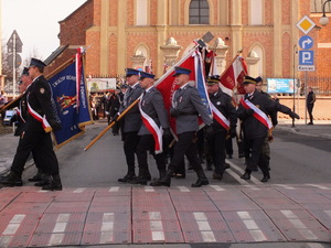 Przemarsz sztandarów i uczestników uroczystości Święta Niepodległości na Rynek. W przemarszu również sztandar Komendy Powiatowej Policji w Proszowicach