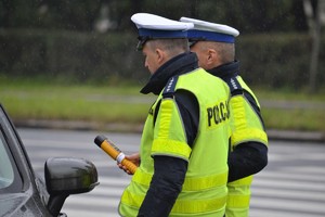 &quot;Dwóch policjantów ruchu drogowego dokonuje badania kierującego samochodem pod kątem zawartości alkoholu w wydychanym powietrzu urządzeniem elektr&quot;