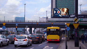 Korek pojazdów stojących przed sygnalizacją świetlną w tle wiadukt i na budynku plakat akcji &quot;zapnij pasy&quot;