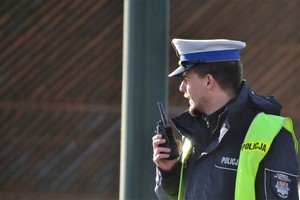 &quot;Policjant ruchu drogowego nadzorujący ruch na drodze, trzymający w ręku krótkofalówkę&quot;