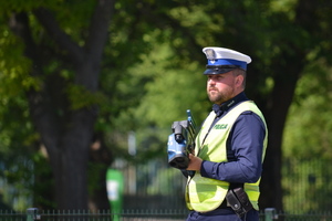 &quot;Policjant ruchu drogowego trzyma w ręce miernik prędkości, nadzoruje ruch na drodze&quot;