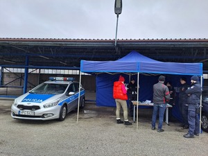 Stoisko edukacyjno-informacyjne wystawione w ramach WOŚP, wraz z materiałami edukacyjnymi, gadżetami. Przy stoisku osoby zainteresowane oraz policjanci z KPP Proszowice.